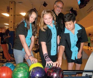 West Valley Bowl Junior Travel League coach Bill Moreno looks on as Emily Isola, 12, Abbigail Hickman, 10, and Jaeden Mah-Bishop, 13, pick out their bowling balls to practice for the 2014 California Pepsi USBC Youth Championship State Finals, which they will compete in this weekend in Southern California. Anne Marie Fuller/For the Tracy Press